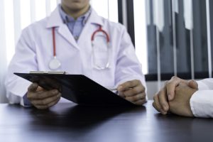Médico fazendo anotações em prancheta durante consulta com paciente