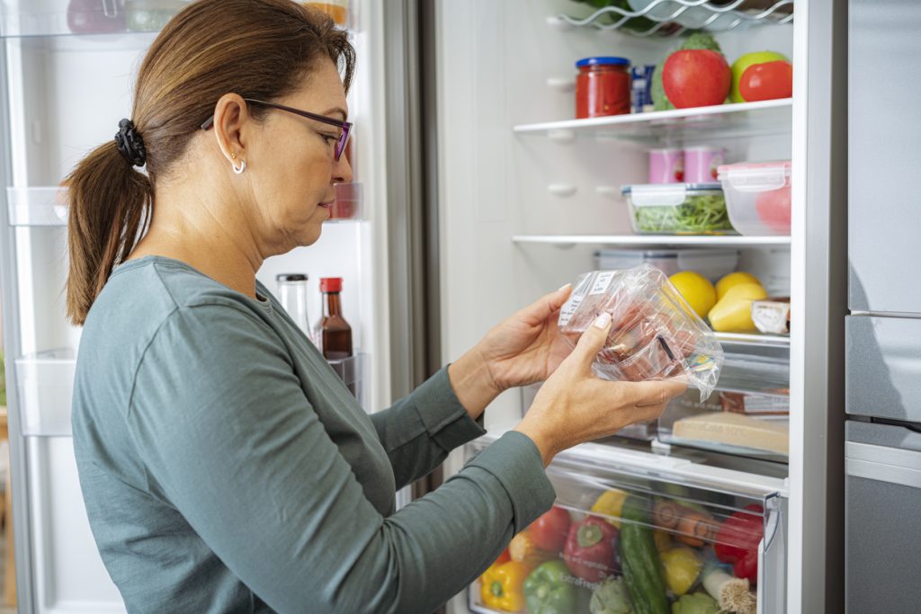 Mulher escolhendo alimentos na geladeira para cardápio semanal equilibrado