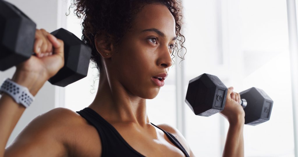 Mulher fazendo exercício com halteres para ganho de massa muscular.
