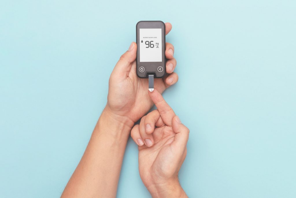 Pessoa realizando teste de glicemia com glicosímetro digital para monitorar os níveis de açúcar no sangue.